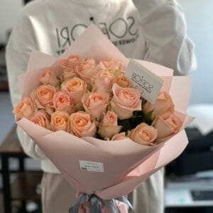 Exquisite 25-stem bouquet of soft pink Tiffany roses, wrapped in premium pink paper and tied with a dark ribbon, showcasing the elegant and sophisticated floral arrangement.